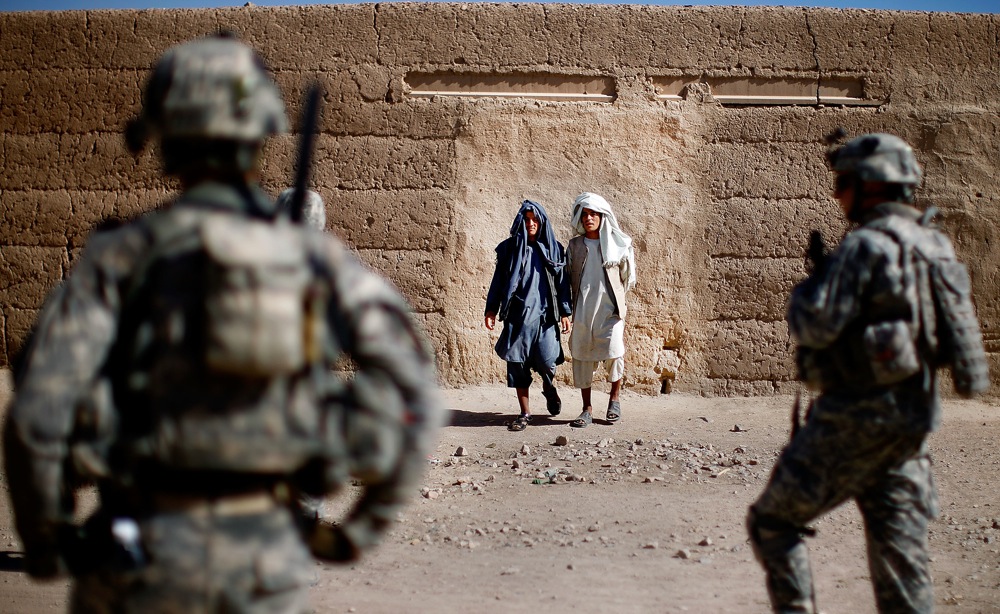 Villagers in Sangeray watch soldiers from Alpha Company during the patrol. The dense urban environment makes it easy for Taliban insurgents to throw grenades at the soldiers and disappear into the surroundings.
