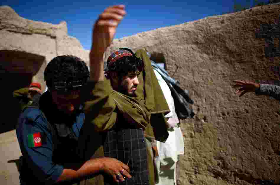 An Afghan national police officer searches a man in Sangeray. The top Taliban leader, Mullah Omar, was born in the Zhari district and many of his first recruits came from here.