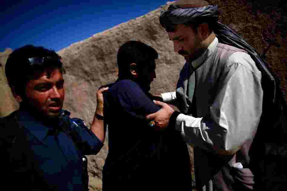 An Afghan national police officer (left) searches a man while Karim Jan (right) holds his arms. The counterinsurgency strategy relies heavily on the police, who live in the community, are closest to the people and should be able to spot insurgents.