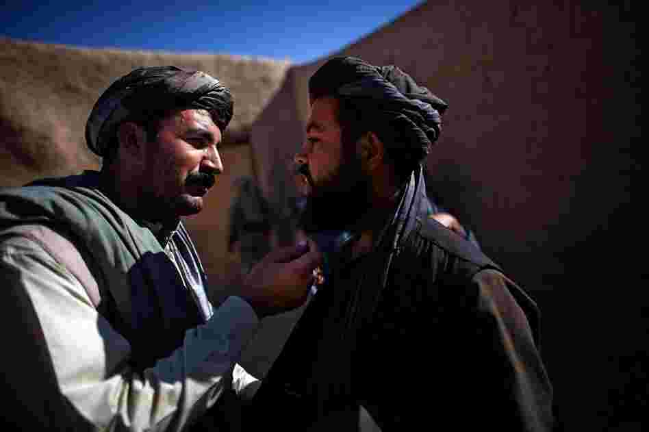 Karim Jan (left) touches the beard of a man he suspects in grenade attacks in the village of Sangeray. The man was arrested after he was questioned. He could not produce a local identity card and was speaking with a foreign accent.
