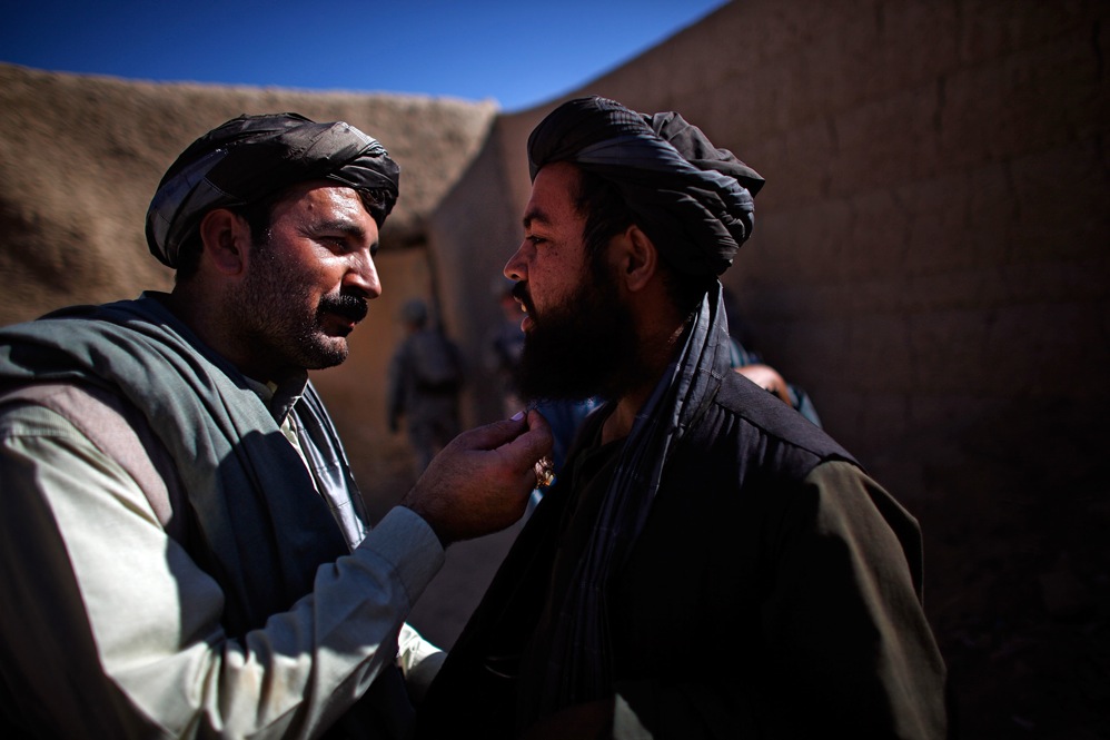Karim Jan (left) touches the beard of a man he suspects in grenade attacks in the village of Sangeray. The man was arrested after he was questioned. He could not produce a local identity card and was speaking with a foreign accent.