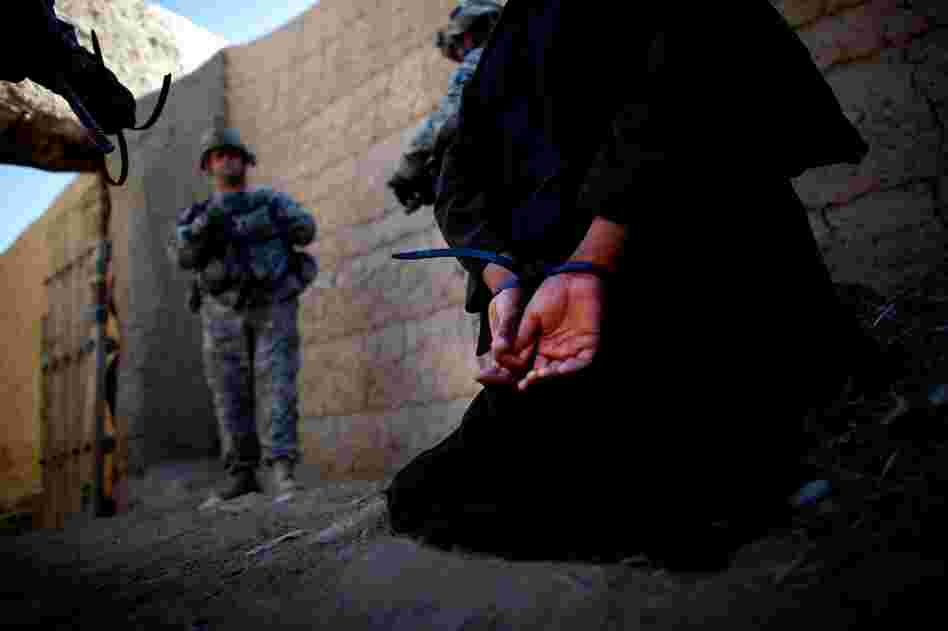 A man suspected of helping the Taliban in grenade attacks is cuffed and detained for further questioning by coalition forces.