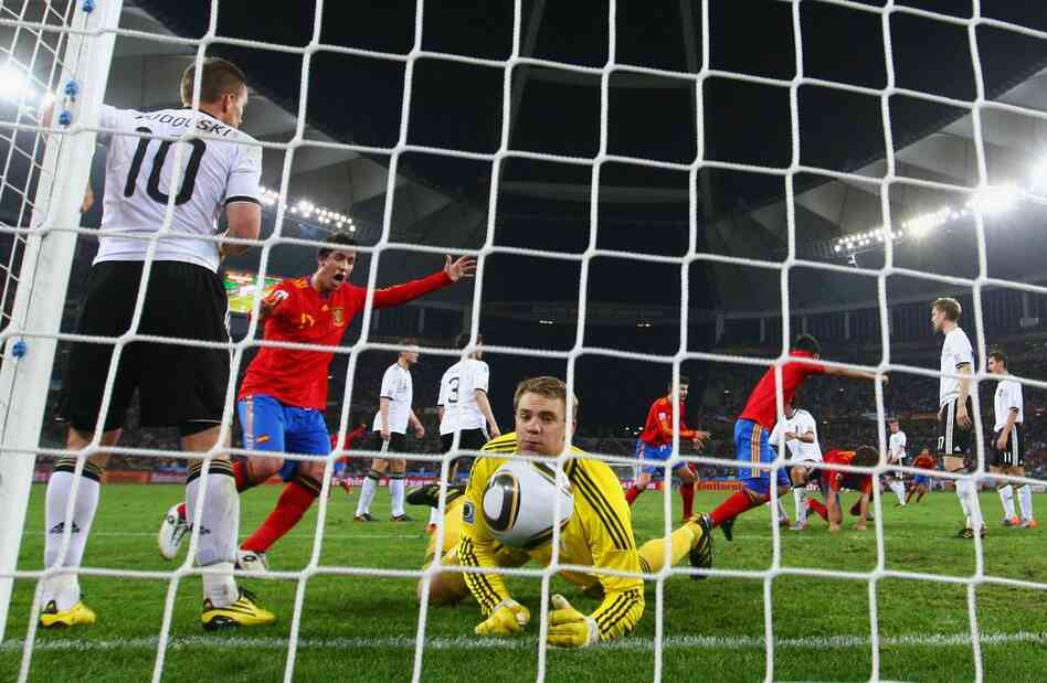 Joan Capdevila of Spain celebrates as teammate Carles Puyol scores the opening goal past Manuel Neuer of Germany during the semifinal match between Germany and Spain. 
