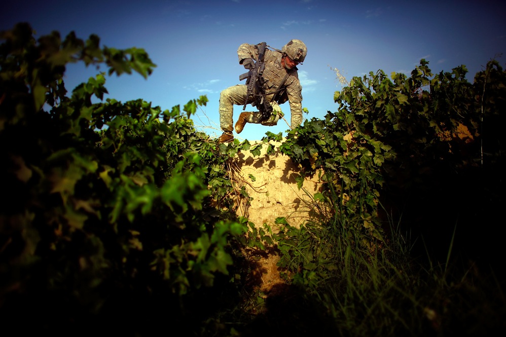 Pfc. James Turner scales an 8-foot-high mud wall. The terrain in the Pashmul area of Kandahar province makes patrolling difficult. Rows of grapevines stand 10 feet tall, and there is knee-deep mud between the rows. Taliban fighters move under the cover of the dense foliage, making the landscape seem more like a jungle than a desert.