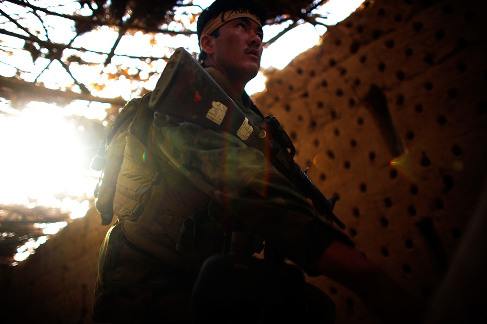 An Afghan National Army soldier walks past a grape-drying barn while looking for sniper hideouts. Buildings in the area are routinely trapped with explosives to be triggered by soldiers. The top Taliban leader, Mullah Omar, was born in the Zhari area, and many of his first recruits came from this region.