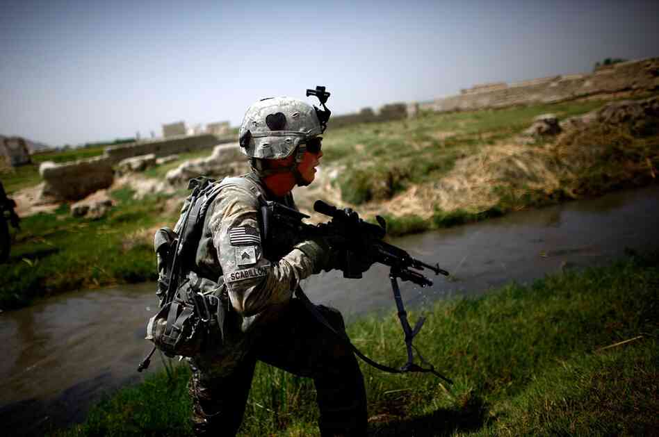 Sgt. Robert Scabilloni runs to take a position while under fire near an irrigation ditch.