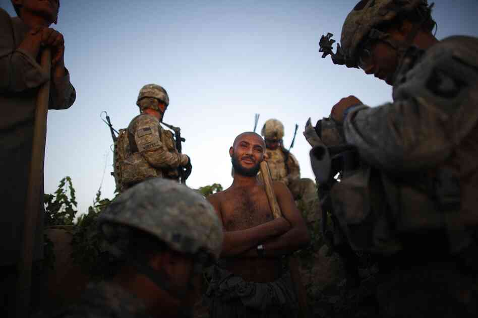 Soldiers stop to talk to a field worker. Many of the workers are not from this area, but brought in for the harvest of grapes — making it even more difficult to sort out who is there to work and who has come to fight.