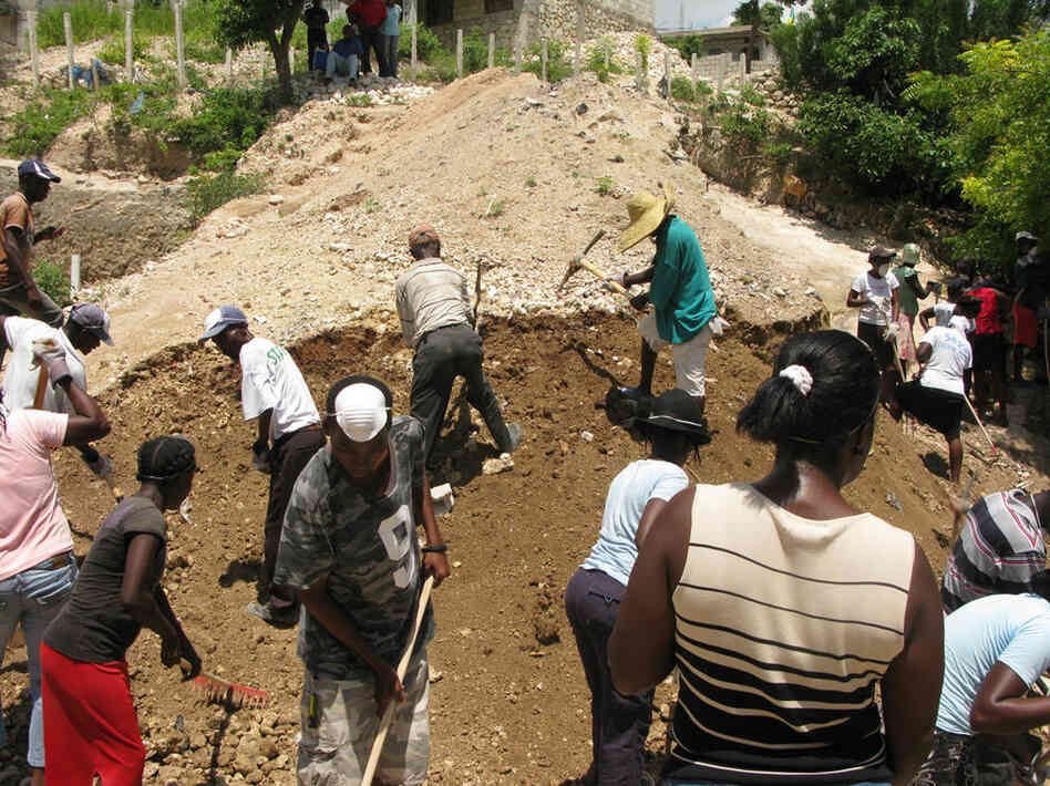 MFD camp in Haiti's capital is a hive of activity as residents work on drainage channels in preparation for the hurricane season. Teams break up the soil with picks, sweep trash and dig drainage channels in the cash-for-work program. 