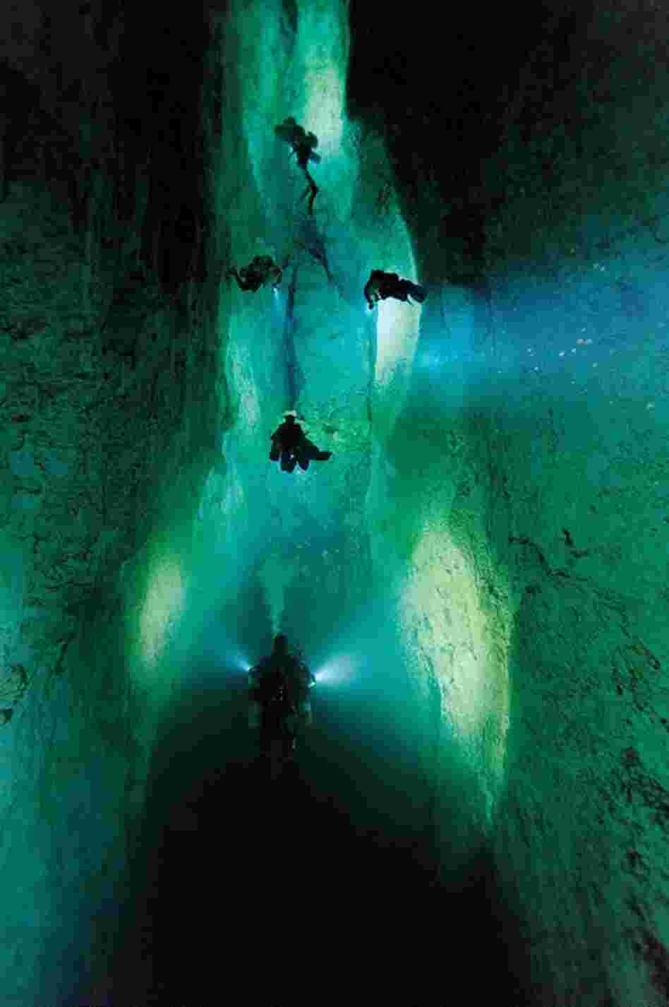 Divers illuminate a passage in Stargate, a blue hole on Andros Island.