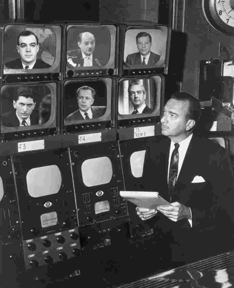 Broadcast journalist Walter Cronkite stands before a group of television monitors showing the CBS News Correspondents for the show Eyewitness. Schorr is seen at the top right. Also pictured: Charles Kuralt, David Schoenbrun, Marvin Kalb, Winston Brudett and Howard K. Smith. 