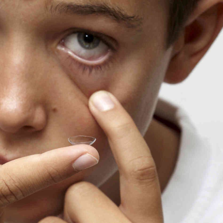 Boy puts contact lens in eye Boy puts contact lens in eye