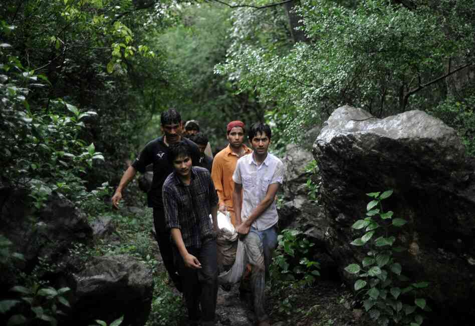 Pakistani volunteers carry remains of victims through the wooded hills. 