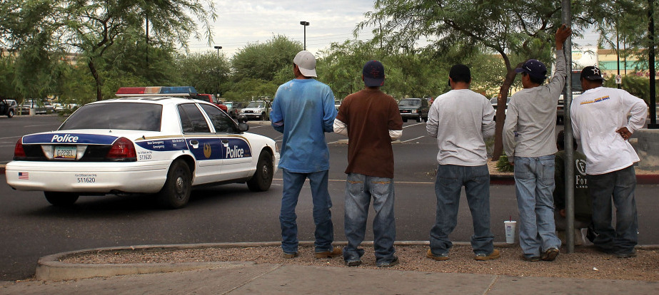 A police cruiser passes by a group of day laborers on a curbside in Phoenix on Monday.<!--Session data-->