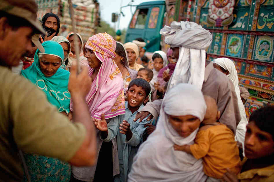 A boy and other displaced villagers plead for relief rations as a soldier waves a stick in an attempt to maintain order in the Sultan Colony army flood relief camp on Aug. 25. Pakistan's agricultural heartland has been devastated, with rice, corn and wheat crops destroyed by floods. 