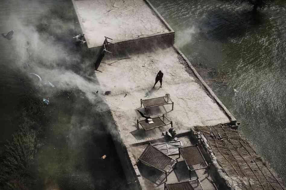 Wind from a Pakistani navy helicopter blows furniture into the water as a man stands on top of his roof during an emergency aid distribution near Bachel in Sindh Province, southern Pakistan.The U.N. said the massive floods have eclipsed the scale of the devastating 2004 Indian Ocean tsunami. 