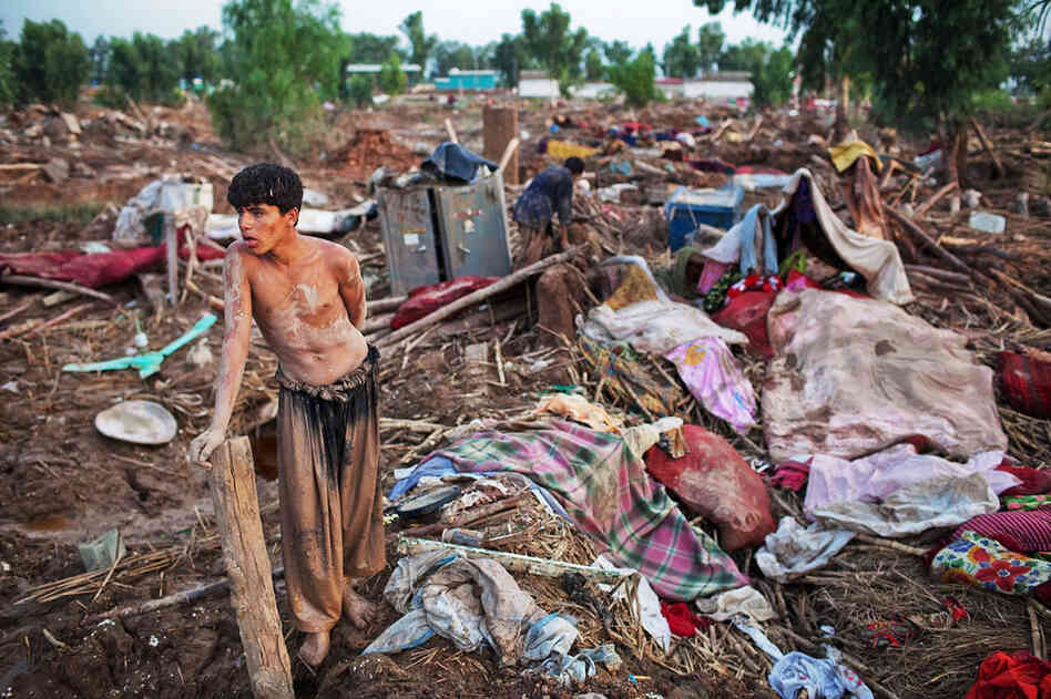 A boy takes a moment to rest after salvaging belongings from his destroyed home in Pabbi. 