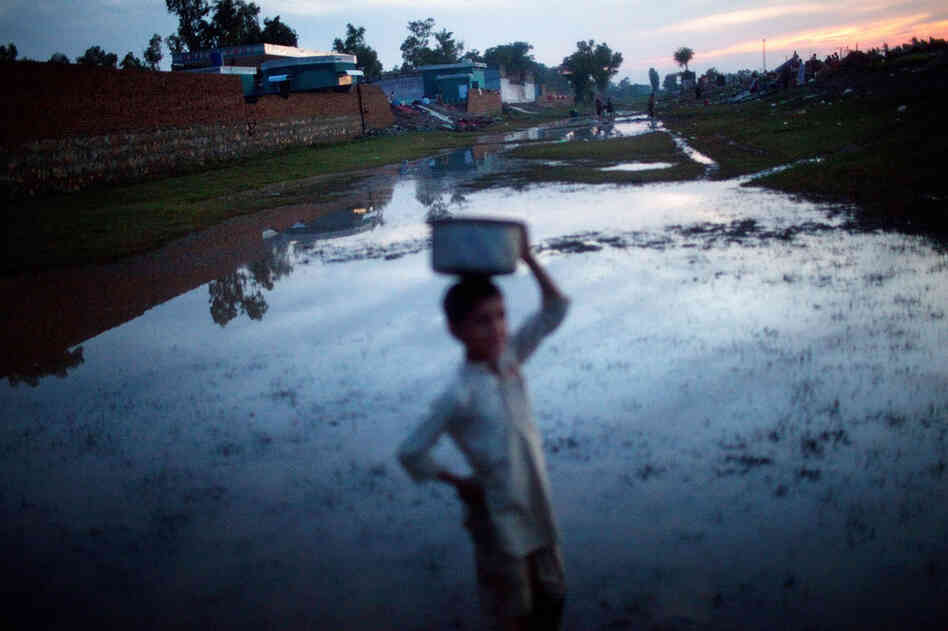 A boy makes his way along a flooded pathway in Pabbi. 