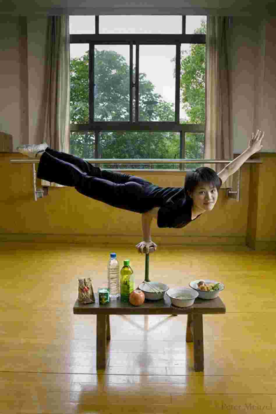 Cao Xiaoli, a professional acrobat, balances on one hand with her daily diet displayed at Shanghai Circus World in China. She is 16 years old, 5 foot 2 and 99 pounds, and on a typical day in June, her caloric intake was 1,700. A few food items in the photo: yogurt, zha paigu (pork ribs), noodles, egg, broth, green tea.