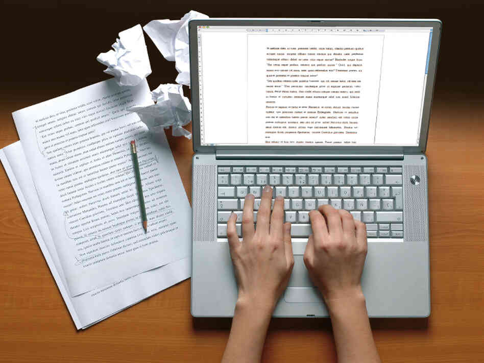 Hands typing on a keyboard with papers Hands typing on a keyboard with papers