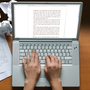 Hands typing on a keyboard with papers