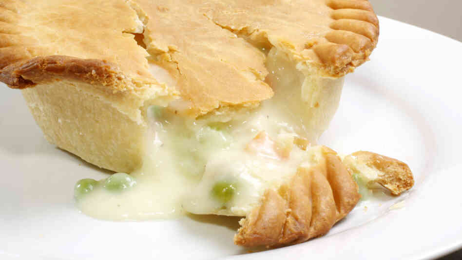 A chicken pot pie oozes its contents onto a plate. A chicken pot pie oozes its contents onto a plate.