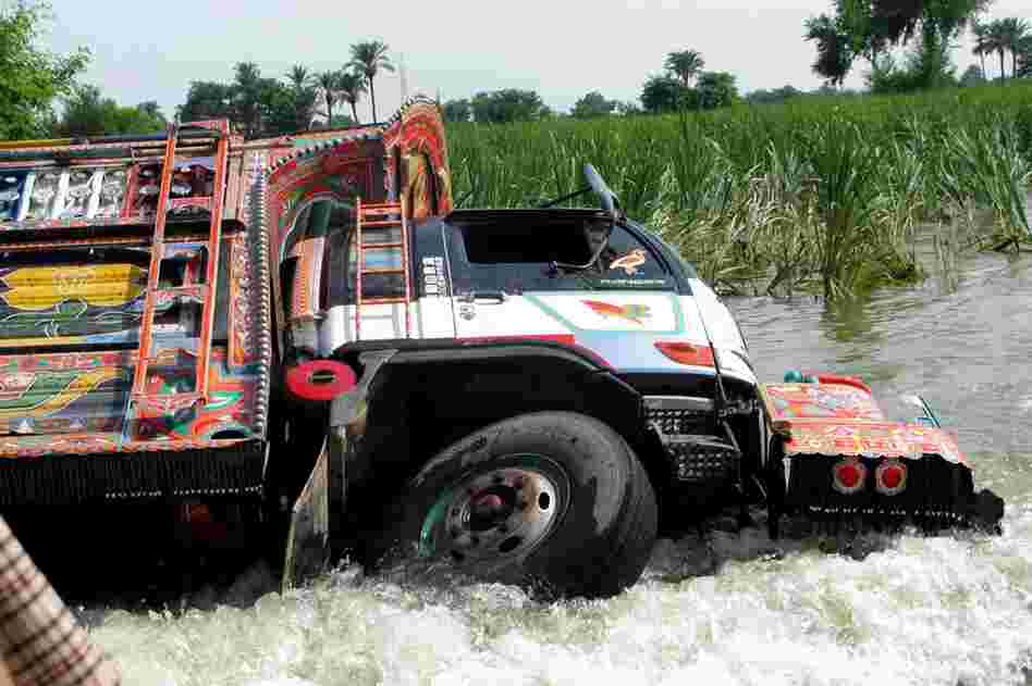 An overturned truck is seen on the main Dera Ghazi Khan-Muzaffargarh Road. The flood waters from the Indus River have buried long stretches of the road. Although many villages are accessible by boat — they are in short supply, leading many to attempt the dangerous crossings in trucks, with deadly consequences.