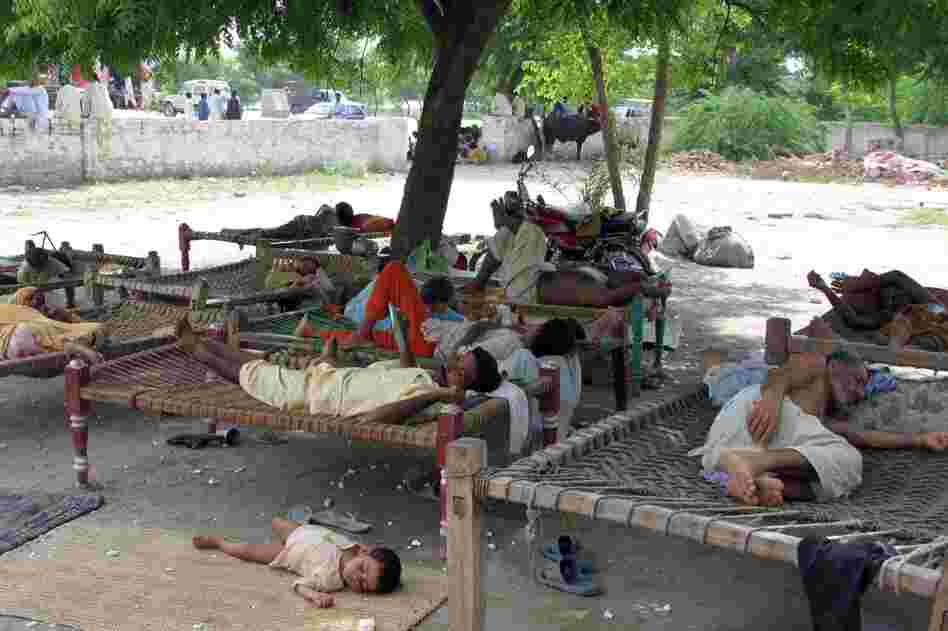 Families rest from the heat in the village of Baseera. Curled up on  traditional "charpoys", people have been forced to take shelter under the sky as large parts of their village were submerged.