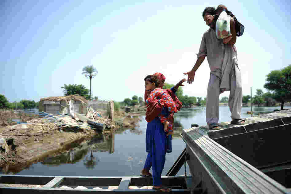 A man helps his wife cross a river in Kasbag Gujarat. The United Nations estimates that 4.6 million people in Pakistan are still without shelter. 