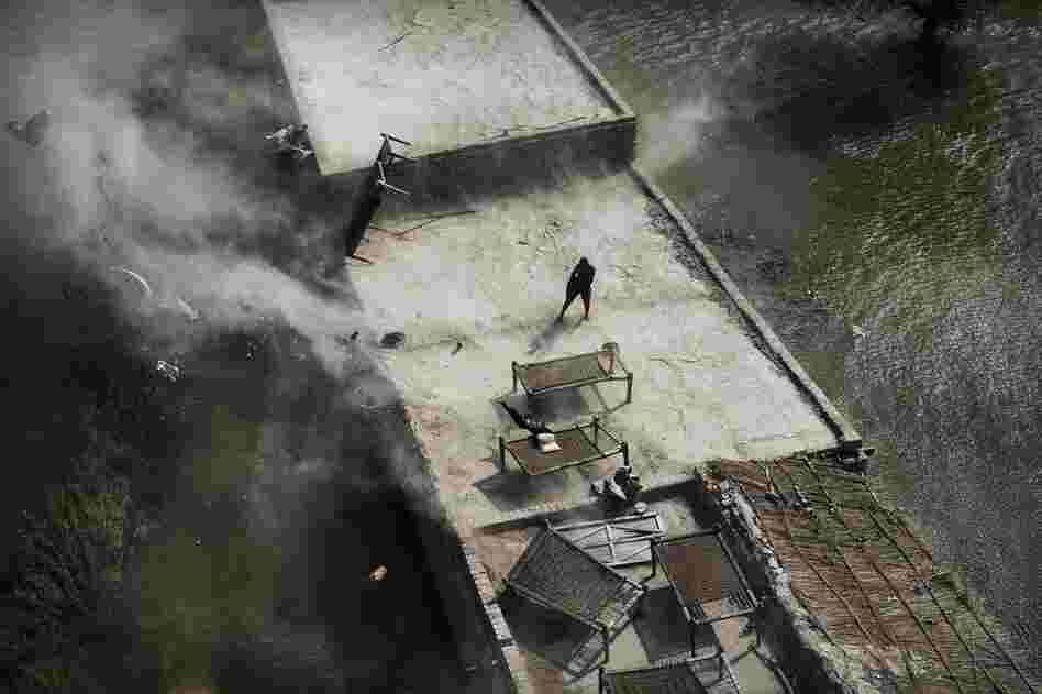 Wind from a Pakistani navy helicopter blows furniture into the water as a man stands on top of his roof during an emergency aid distribution near Bachel in Sindh Province, southern Pakistan.The U.N. said the massive floods have eclipsed the scale of the devastating 2004 Indian Ocean tsunami. 