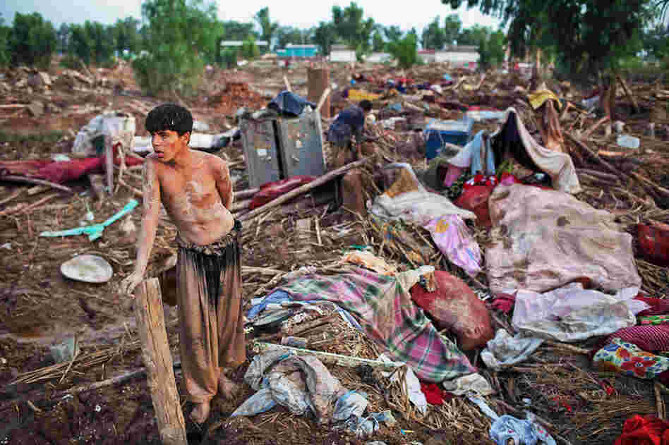A boy takes a moment to rest after salvaging belongings from his destroyed home in Pabbi. 