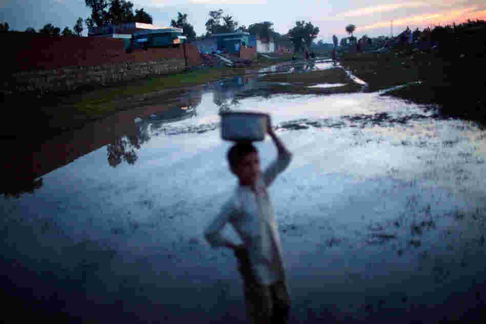 A boy makes his way along a flooded pathway in Pabbi. 