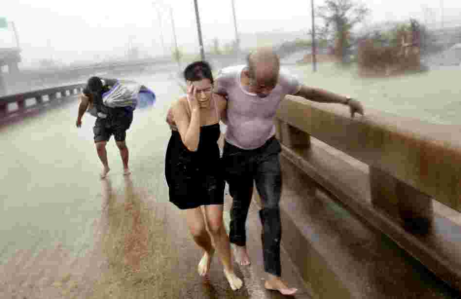 Otis Brown, 67, holds on to Jennifer Cooper, 33, as they fight their way through the wind driven rain of Hurricane Katrina with Albert Jean, 50, up an Interstate 610 off-ramp after escaping roof-level floodwaters in the Clermont Driver area of New Orleans. The three were part of a larger group who escaped the floodwaters by taking an aluminum motorboat to the off-ramp on Aug. 29, 2005. (Jim Win...