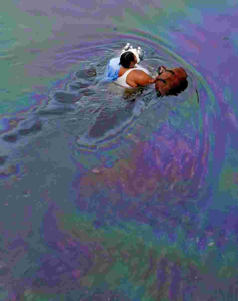 A New Orleans resident wades through floodwaters coated with a fine layer of oil in the flooded downtown area on Aug. 30, 2005. 