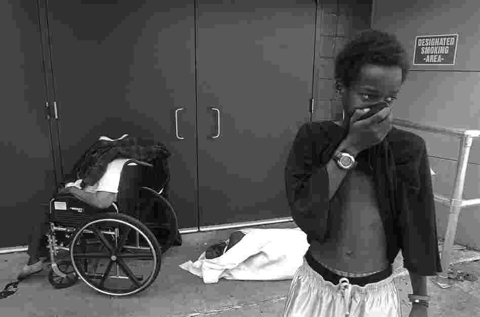 A young boy covers his face from the stench of the two bodies left by the side entrance of the Ernest N. Morial Convention Center in New Orleans on Sept. 2, 2005. 