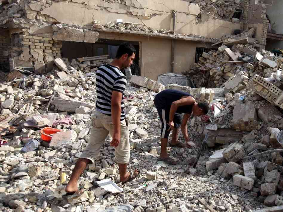 Iraqis survey a collapsed building in Baghdad the day after several bombings across Iraq. Iraqis survey a collapsed building in Baghdad the day after several bombings across Iraq.