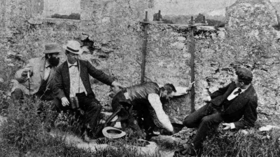 Group of men kiss the Blarney Stone in Ireland circa 1880