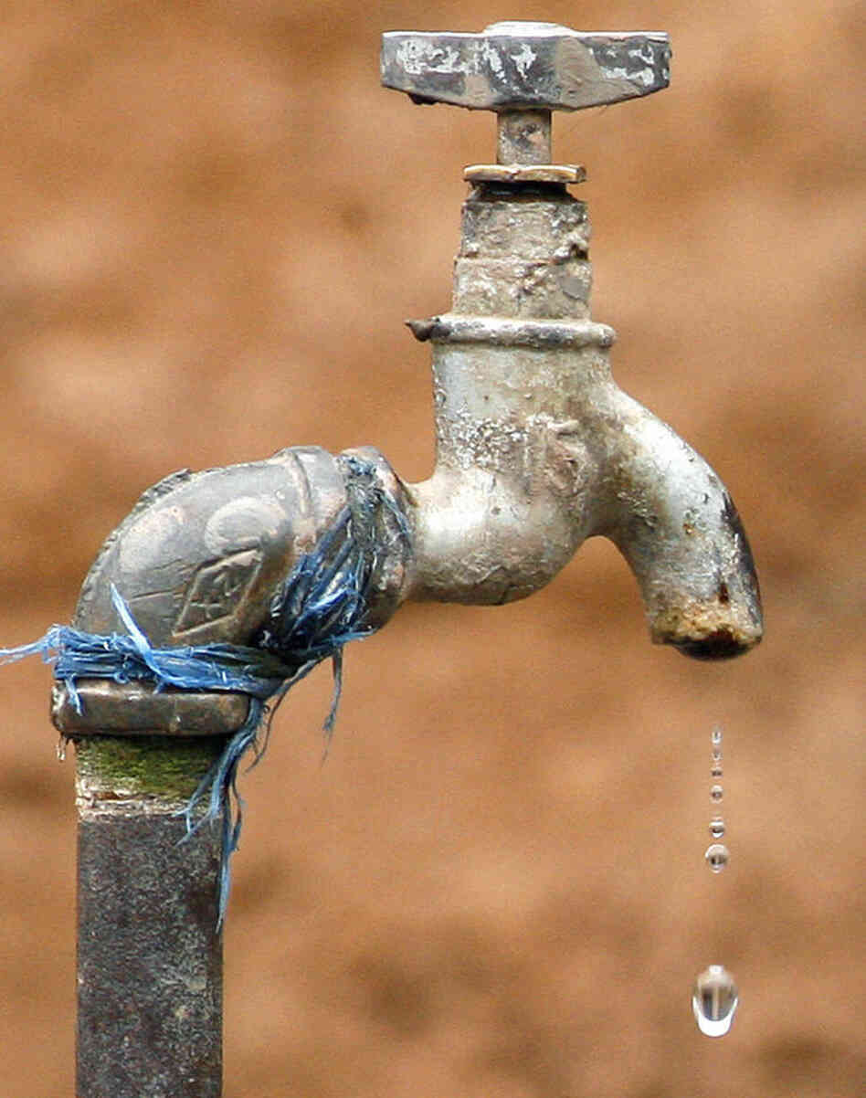A drop of water drips down from a tap. A drop of water drips down from a tap.