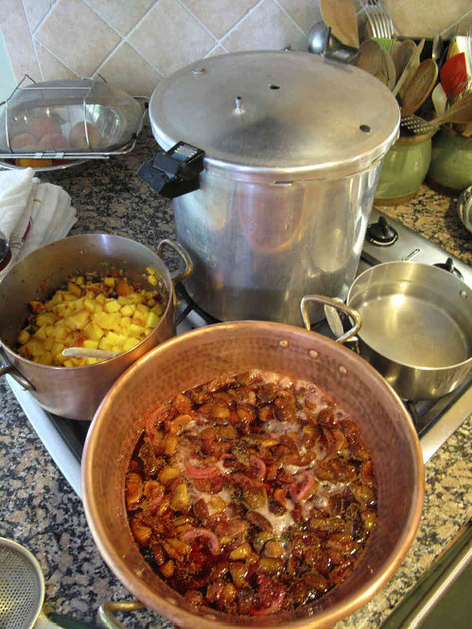 Peach salsa (center left) and fig confiture cook while the canner sits nearby, ready for sealing them in jars. Though Barrow uses a pressure canner for her home canning, she teaches her classes using the boiling water bath method.