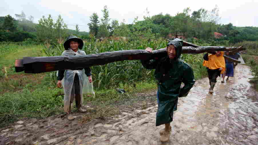 Villagers from Guangmenyan move roof beams and bamboo poles to take with them to their new homes. Villagers from Guangmenyan move roof beams and bamboo poles to take with them to their new homes.