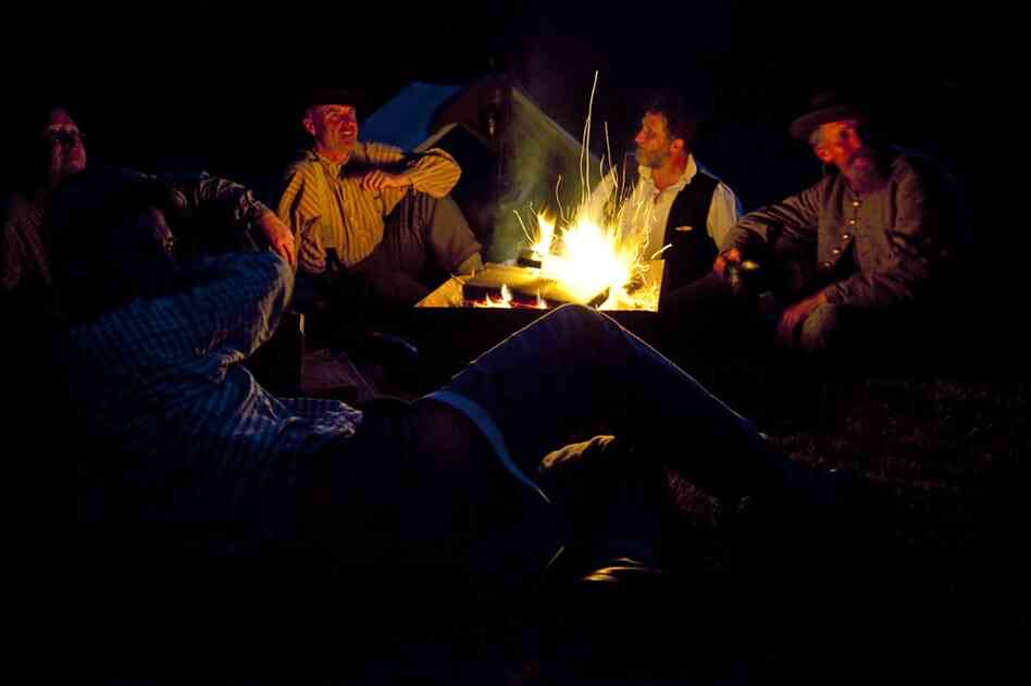 Members of the ACWS 18th Virginia Infantry sit around a fire at their part of the Confederate camp the night before a re-enactment for the public in Market Deeping, England.