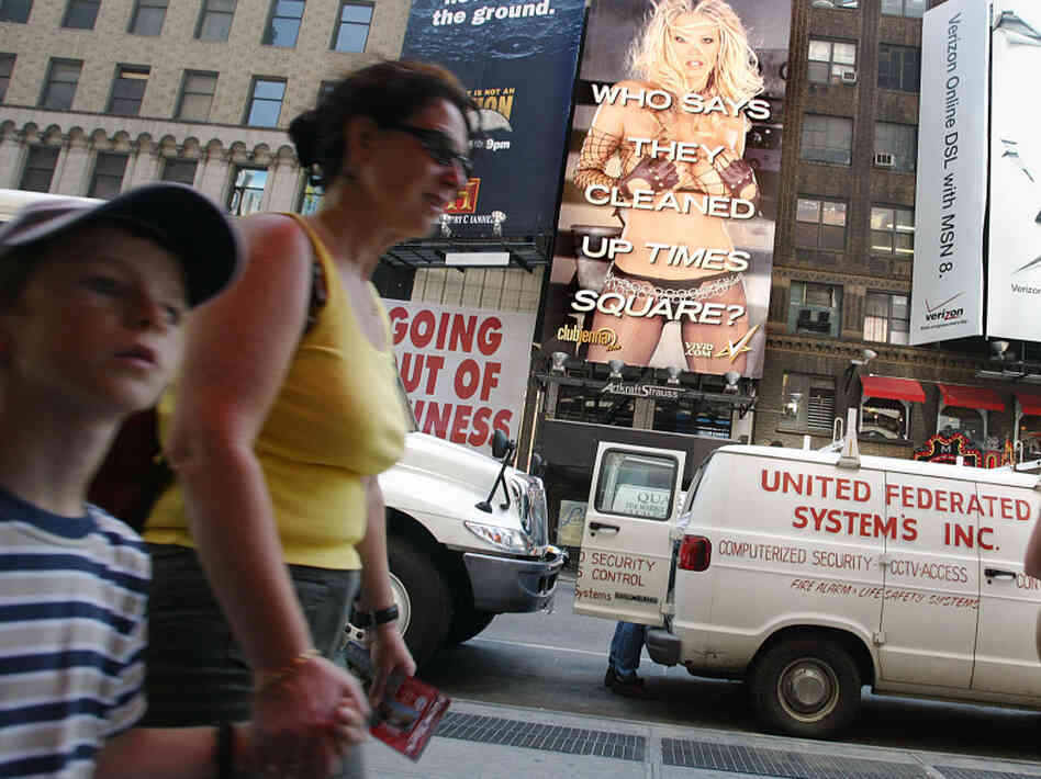 Child walks hand in hand with mother with porn billboard in background. Child walks hand in hand with mother with porn billboard in background.