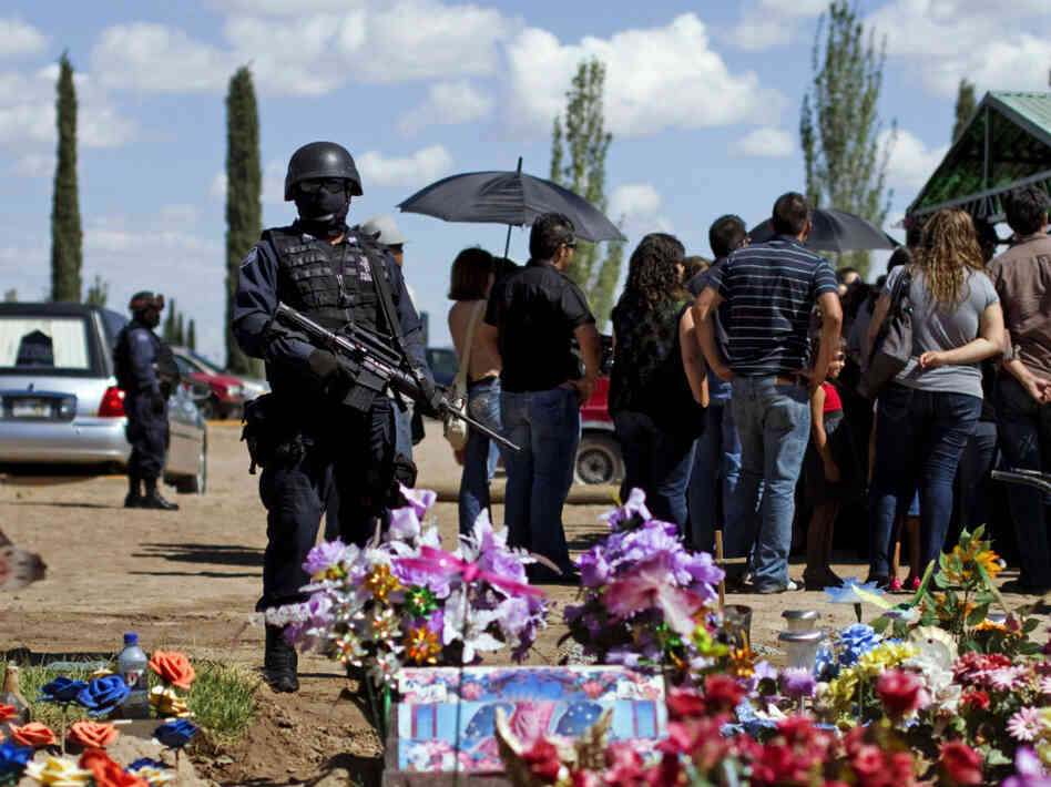 Federal police officers stand guard during the burial of newspaper photographer Luis Carlos Santiago.