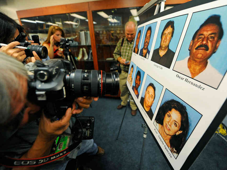 Photographers photograph a display of current and former Bell council members who were arrested.
