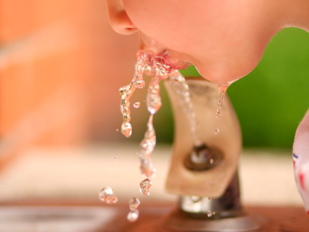 Child drinks from school water fountain.