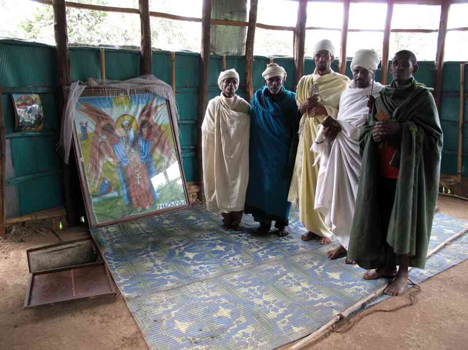 The trap door in the floor to the left of these religious men offers a view of slow-moving spring water said to be the source of the Blue Nile. The water at Gish Abay is believed to be holy. The faithful drink some everyday for good health.