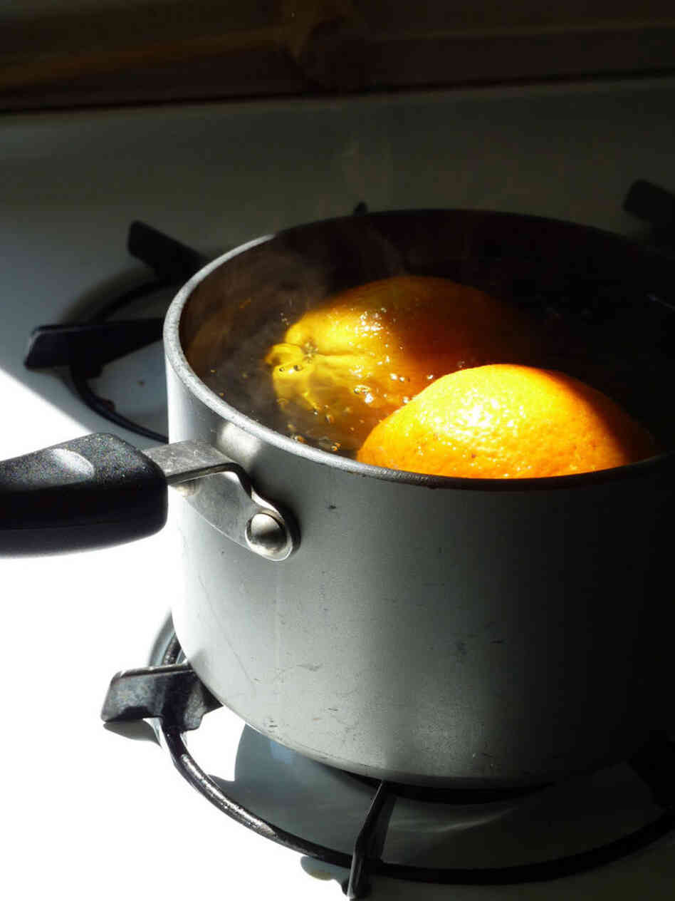 Oranges simmer in water in a pot on the stove Oranges simmer in water in a pot on the stove