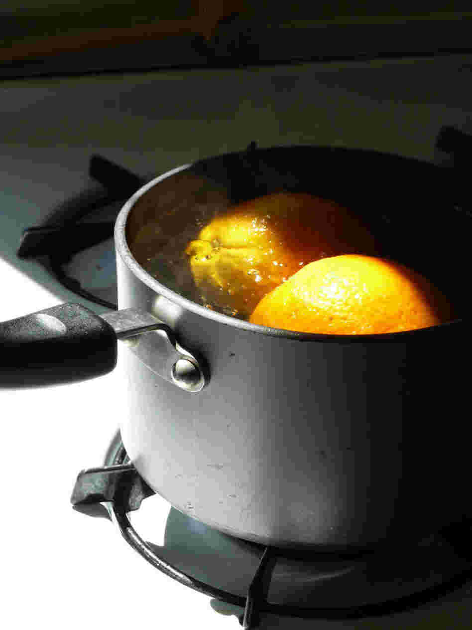 Oranges simmer in water in a pot on the stove Oranges simmer in water in a pot on the stove