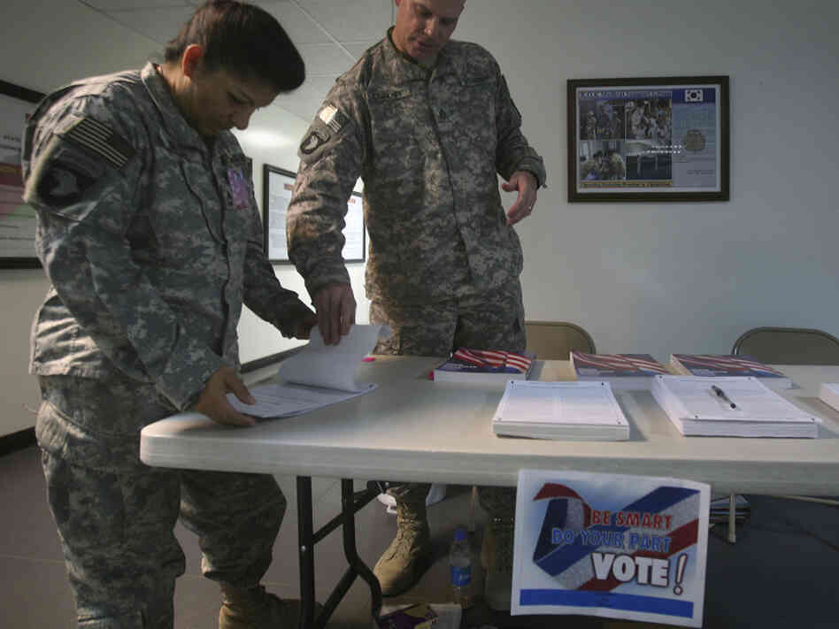 A U.S. member of Combined Joint Task Force 101, left, checks a voting ballot