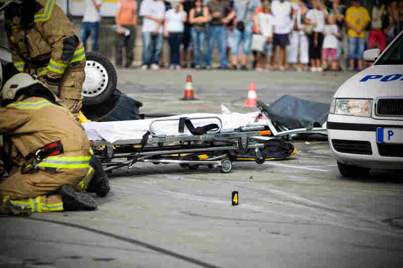 Firefighters tend to an injured person after a car accident. Firefighters tend to an injured person after a car accident.