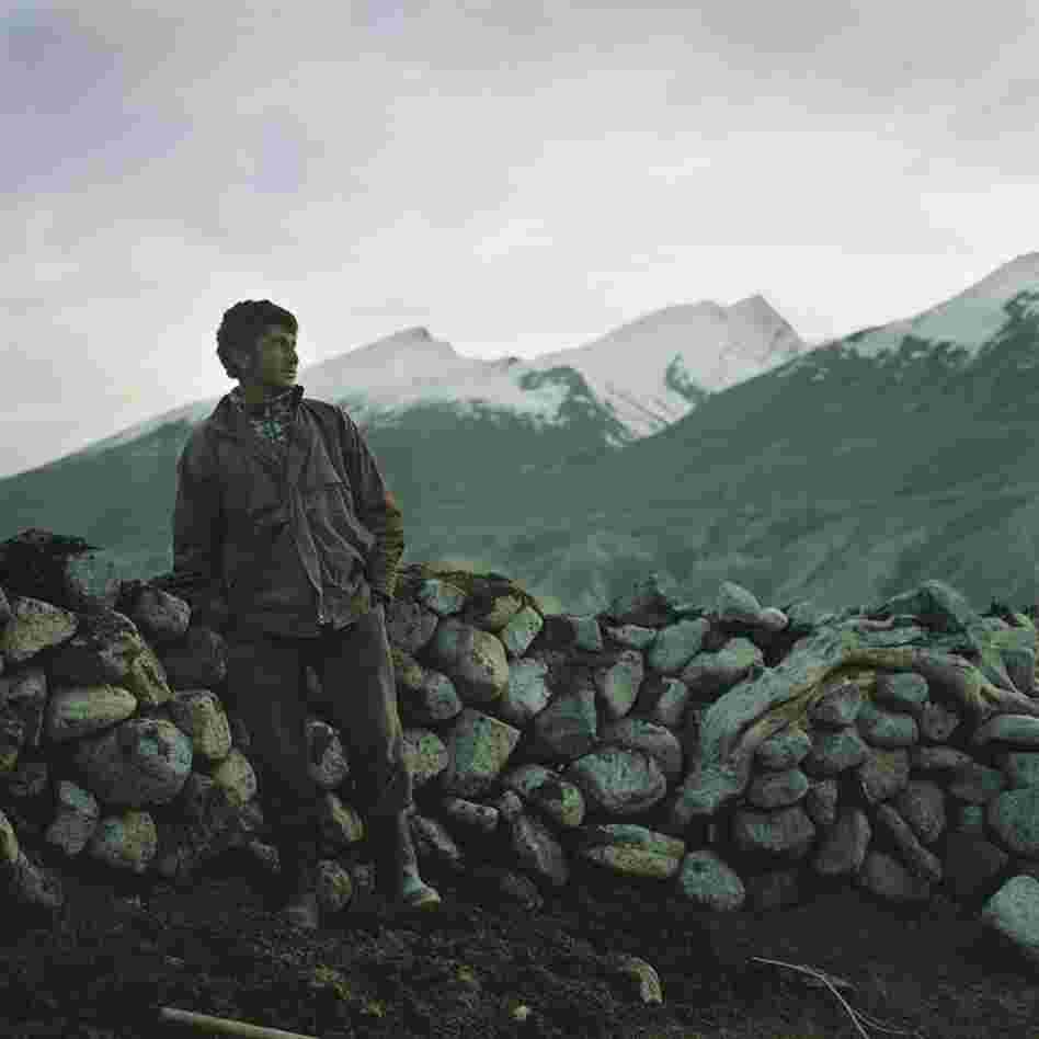 A young Wahki shepherd stands next to a sheep and goat pen after herding the flock in for the night.